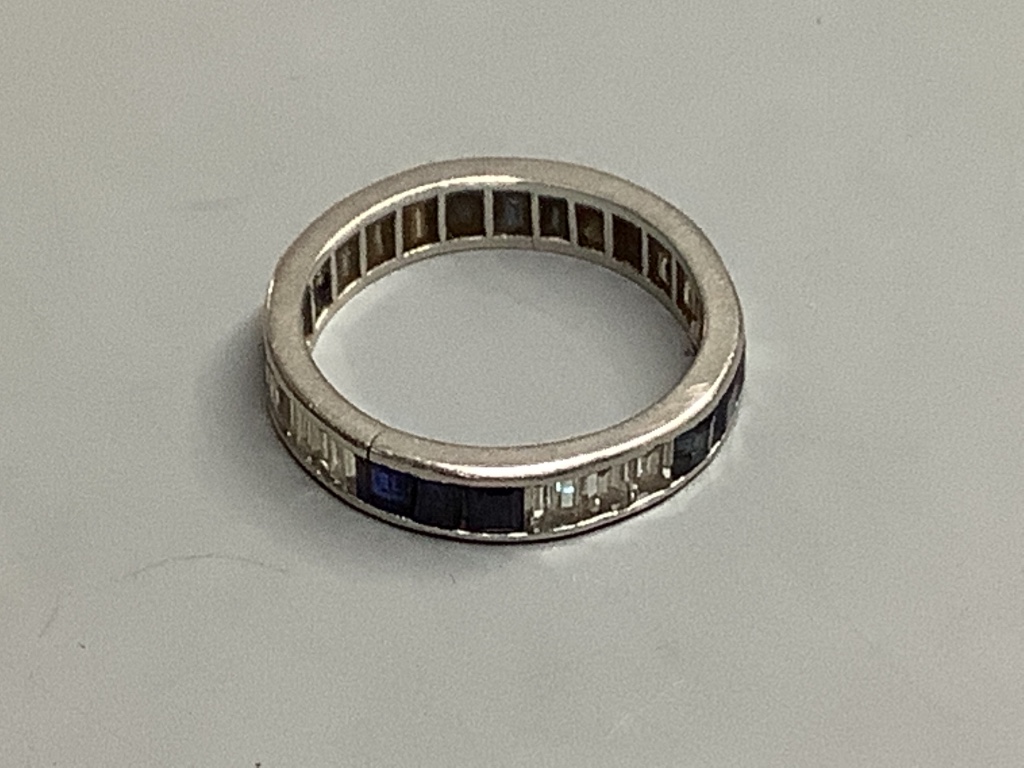 An 18ct white gold calibre-cut diamond and sapphire eternity ring